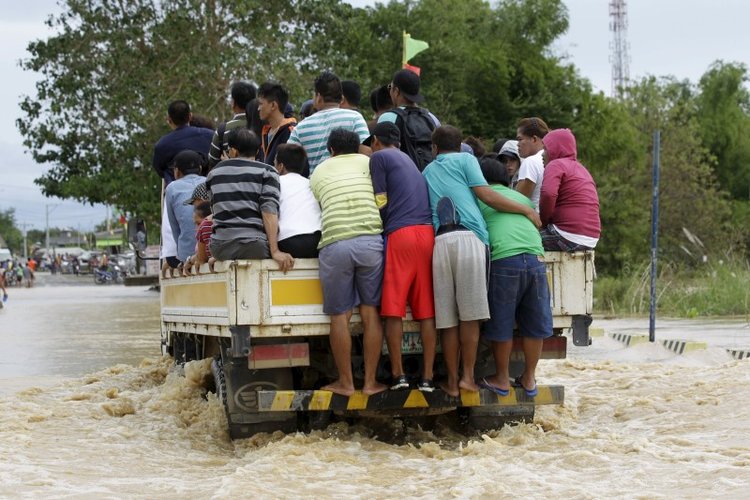 Người dân bám trên xe tải để đi qua con đường ngập nước sau trận mưa lớn.